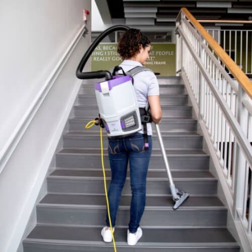 Woman using small backpack vacuum proteam gofit 3 on stairs